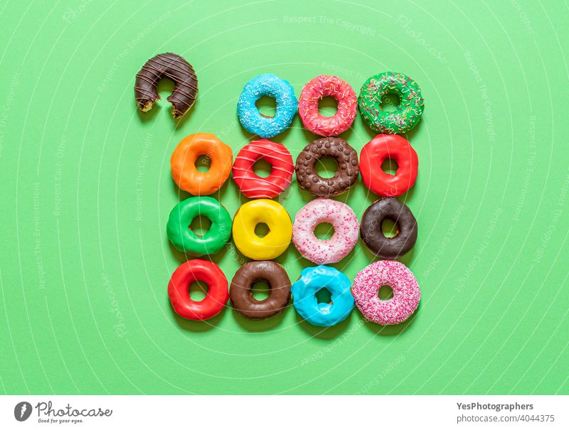 Chocolate donuts with multicolored icing, top view on a green background. above view aligned assorted baked bitten blue cake chocolate colorful cuisine cut out