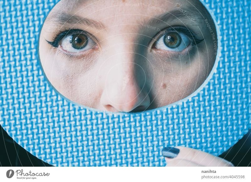 Close up of young woman's eyes and her face covered by a blue circle lips real green eyes eyeliner covering color sexy sensual attractive red lips contrast