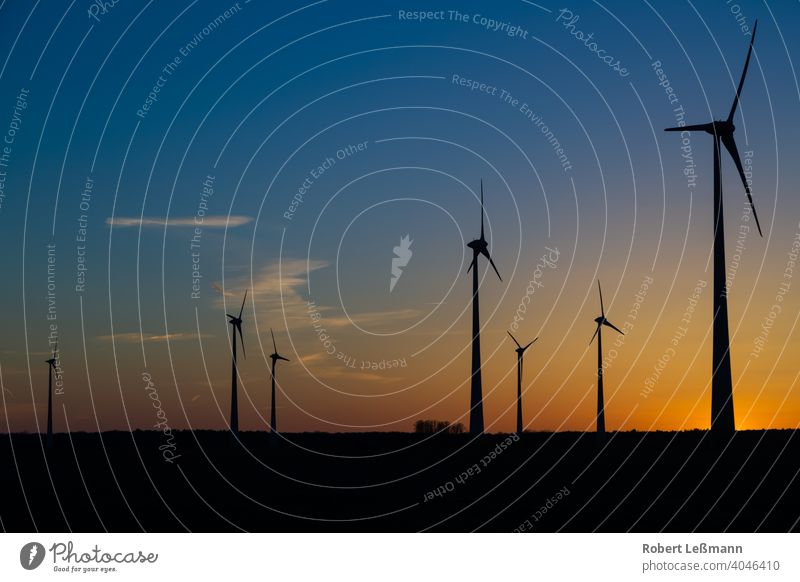 many wind turbines at sunset stand on a field and produce electricity windmills eco-power Eco-friendly Climate protection Sunset Electricity Silhouette