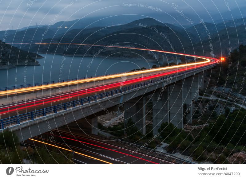 Long exposure of a mountain landscape with a reservoir surrounded by a highway illuminated by car lights. long exposure night bridge Sierra Nevada mountains