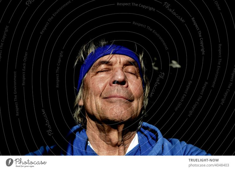 Senior, who hasn't been able to visit his barber shop in a while thanks to pandemic rules, lets the spring sun caress him, closes his eyes in a dream, and takes a selfie in a blue hoodie and headband.