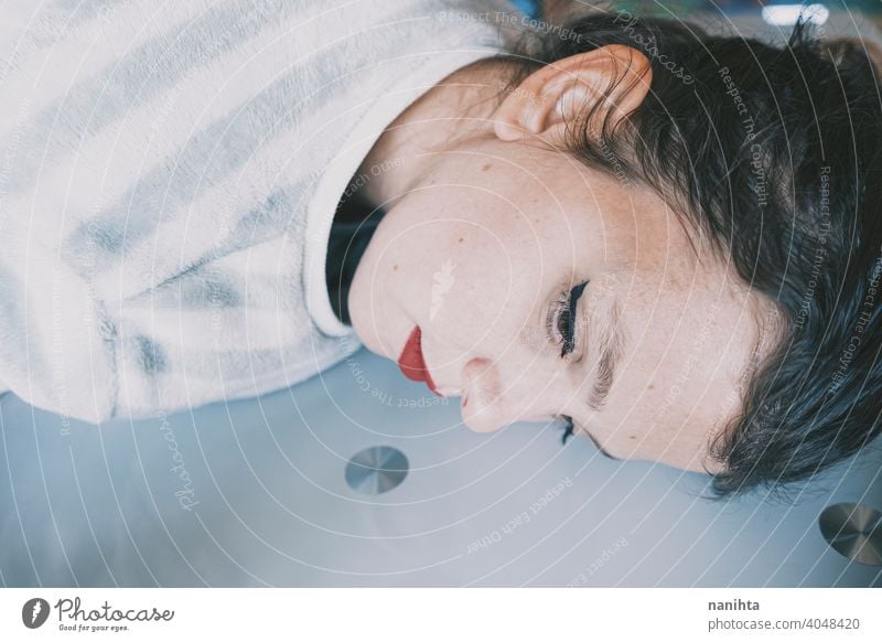 Portrait of a young woman leaning her face against a cold glass table depression blue sad mental health psychology sadness depressive white reflection mirror