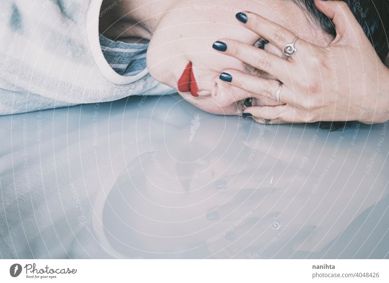 Portrait of a young woman leaning her face against a cold glass table depression blue sad mental health psychology sadness depressive white reflection mirror