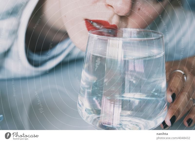 Portrait of a young woman hidden by a glass with a transparent drink depression blue sad mental health psychology sadness depressive cold white reflection