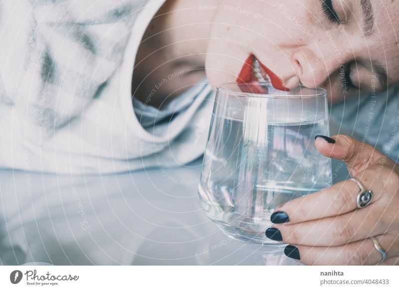 Portrait of a young woman hidden by a glass with a transparent drink depression blue sad mental health psychology sadness depressive cold white reflection