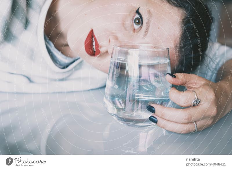 Portrait of a young woman hidden by a glass with a transparent drink depression blue sad mental health psychology sadness depressive cold white reflection