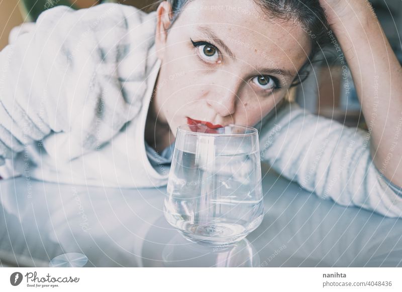 Portrait of a young woman hidden by a glass with a transparent drink depression blue sad mental health psychology sadness depressive cold white reflection