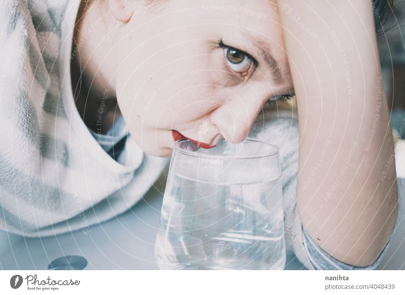 Portrait of a young woman hidden by a glass with a transparent drink depression blue sad mental health psychology sadness depressive cold white reflection