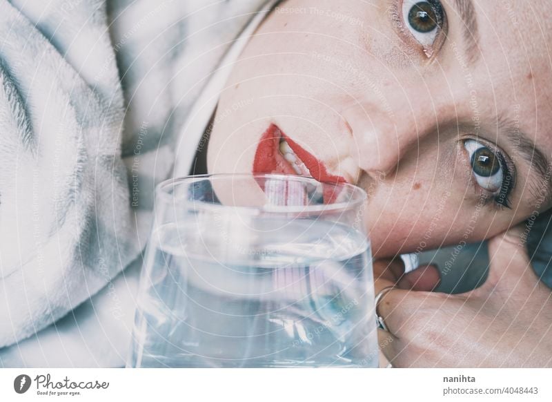 Portrait of a young woman hidden by a glass with a transparent drink depression blue sad mental health psychology sadness depressive cold white reflection