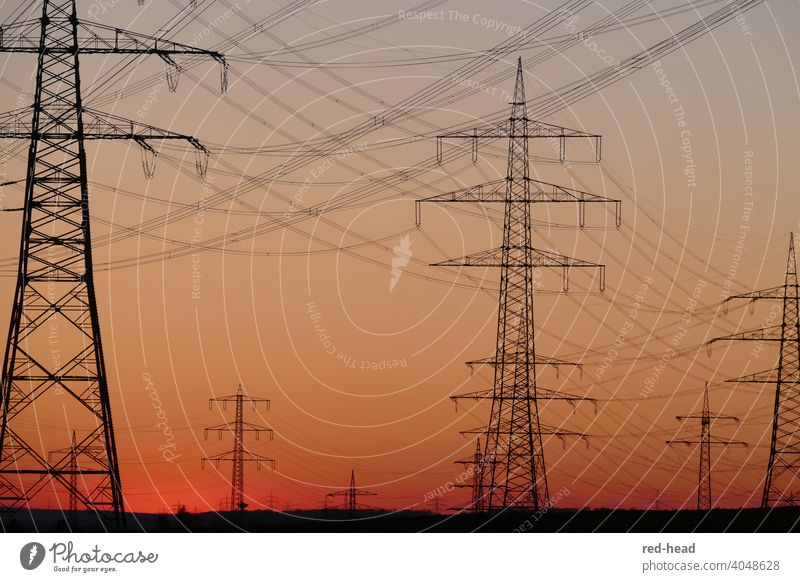 High voltage pylons in front of orange-red evening sky, low horizon, crossing lines, pylons partly cut off Electricity pylon Energy High voltage power line Dusk