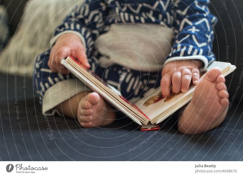 Young baby touching picture in a board book; childhood milestone 8 months old 0-12 months first year development hardback mimic developmental point pointing