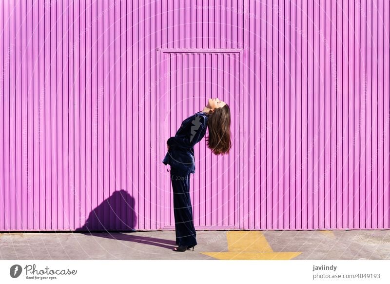 Woman wearing blue suit posing near pink shutter. woman hairstyle fashion model building blind fuchsia purple moving girl person lifestyle female urban