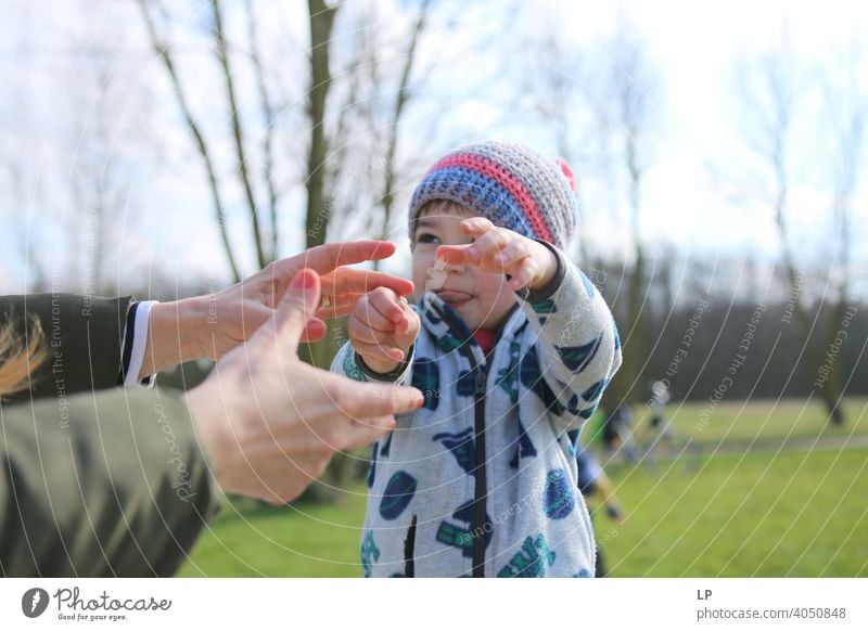 small child reaching hands toward his mother Looking away Upper body Dependability Exterior shot Multicoloured Help Love Together Safety (feeling of) Protection