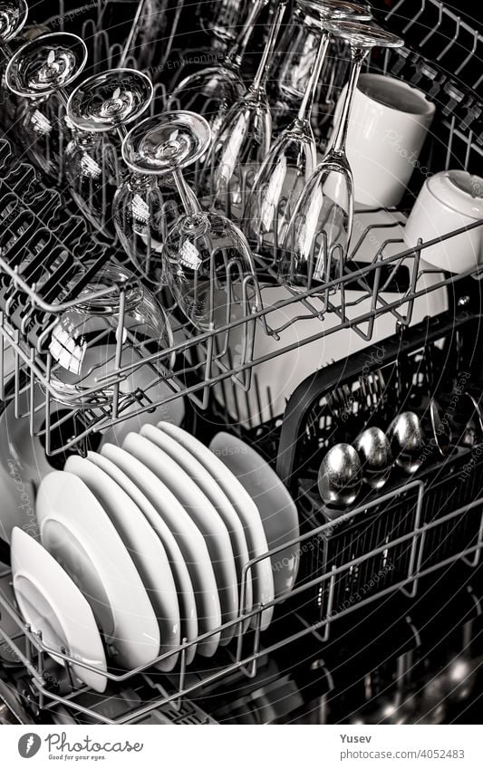 Crystal clean shiny plates and transparent glasses in a dishwasher. Tableware, kitchen, housework. Close-up. Vertical shot. crystal tableware close-up