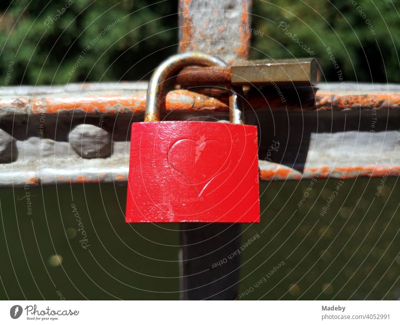 Red love lock with heart as engraving on a rusty bridge railing on a bridge over the Bega in Lemgo near Detmold in East Westphalia-Lippe Love padlock Loyalty