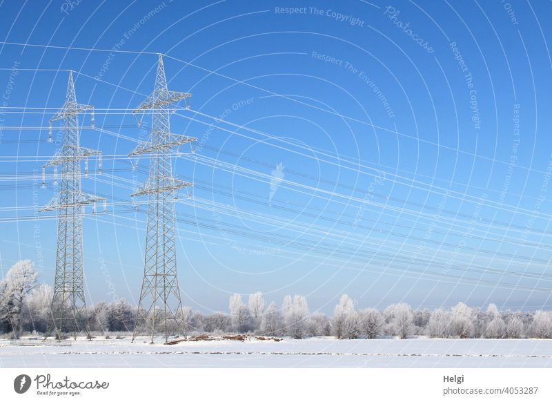 Winter wonderland - two huge power poles, power lines and the trees in the landscape are covered with hoarfrost Power poles Power lines Energy Energy generation