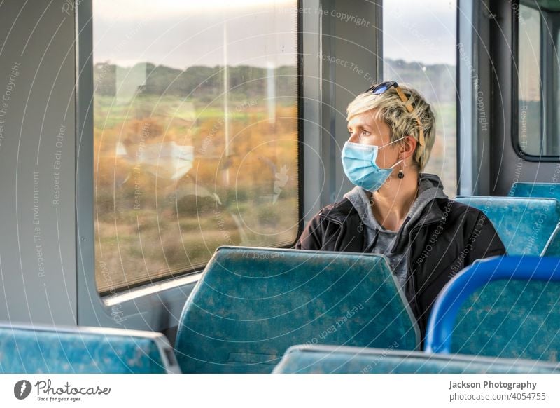 Woman wearing surgical mask looking through the window in a train pandemic woman serious sad copy space public transport covid19 caucasian corona virus lockdown