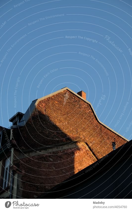 Old firewall of an old building made of brown brick in the light of the evening sun in front of a bright blue sky in the summer in the Hanauer Landstraße in the Ostend of Frankfurt am Main in Hesse