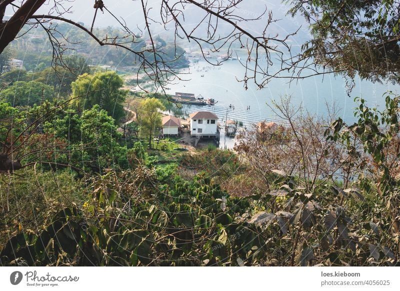 Top view on village coast along lake Atitlan through trees, San Juan la Laguna, Guatemala atitlan san juan aerial top guatemala beach local mountain water