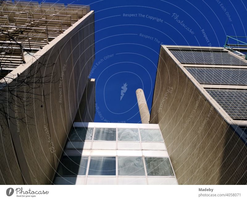 Building of the Goethe University with chimney of a power plant in front of a bright blue sky in sunshine in Frankfurt am Main in Hesse, Germany