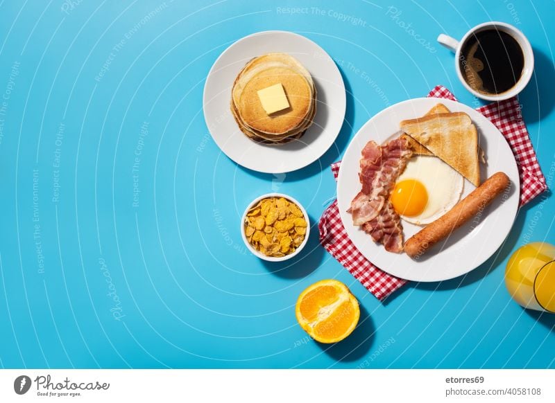 Traditional American breakfast on blue background amrican bacon bread butter cereals dish egg fat food fried fruit juice nutrition orange pancakes plate protein