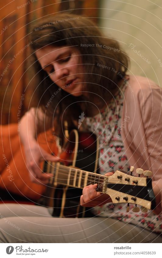 immersed in guitar playing - young brunette woman sits on sofa at home and plays guitar Music Guitar Woman Musician Playing Make music Art cabaret