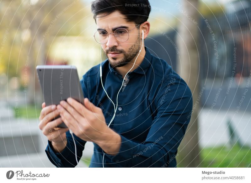 Young man having a video call on digital tablet outdoors. young technology mobile working social network touchscreen outside online concept display wireless