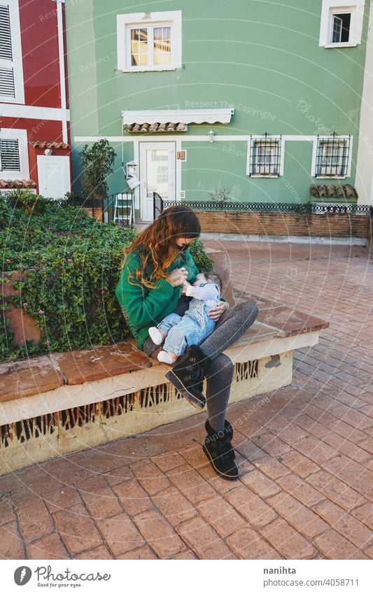 Young woman breastfeeding her baby outdoors in a sunny day young mother mom family green holidays leisure health blonde care childhood parenthood babyhood