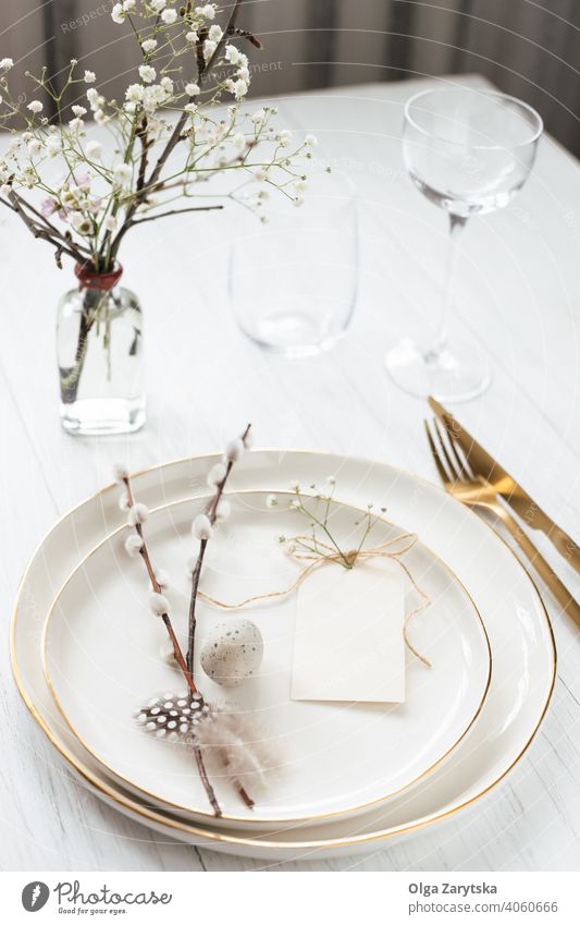 Easter table setting with willow twigs, quail eggs and tag. easter plate decor idea lable empty blank cutlery golden rim white glass flower