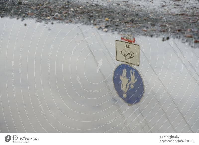 Pothole on a footpath with traffic sign, pedestrian and cycle traffic only free, reflected in a large puddle in a pathway Road sign Puddle dilapidated