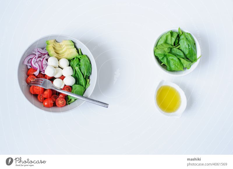 breakfast healthy diet bowl with cherry tomatoes, avocado, spinach leaves, Mozzarella and red onion with olive oil dressing vegetable salad food lime juice