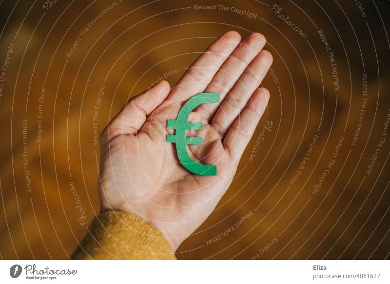 A person holds a green euro sign in his hand. Concept of investing, investing and consuming money sustainably. Green Money Euro symbol Sustainability moor