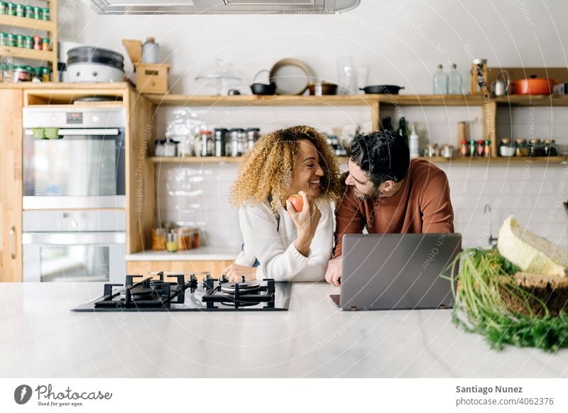 Couple looking at laptop in kitchen. middle age couple love cooking home cozy caucasian relationship preparing female happy person stove woman beautiful girl