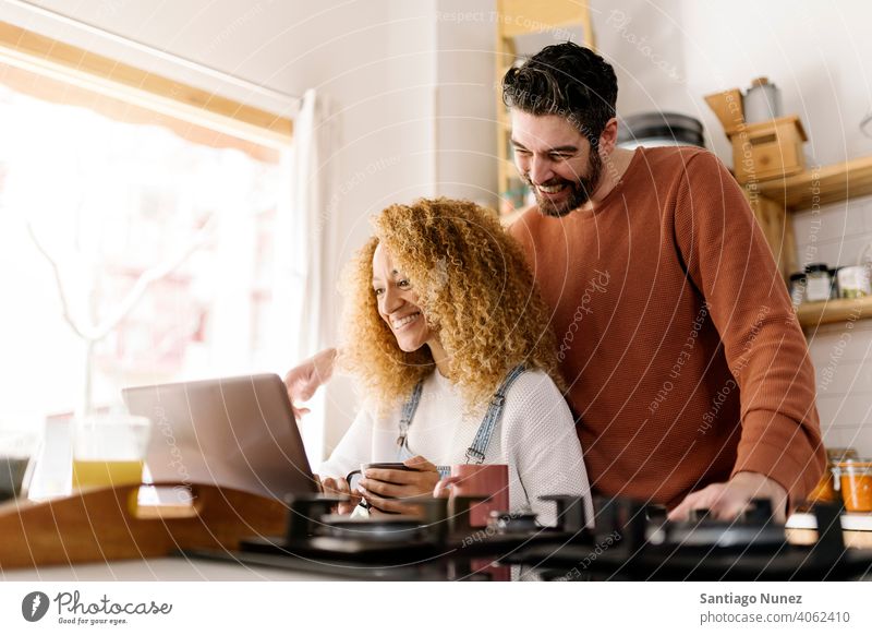 Couple looking at laptop in kitchen. middle age couple love cooking home cozy caucasian relationship preparing female happy person stove woman beautiful girl