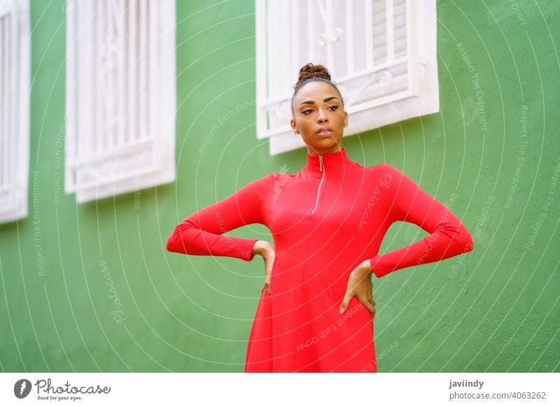 Young black woman in red dress in front of a green wall bow serious hairstyle model beauty fashion pretty portrait girl young female person lady summer white