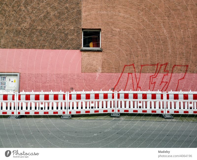 Facade with single window, rectangles in brown and pink, graffiti and red and white construction fence in Offenbach am Main in Hesse Apartment Building