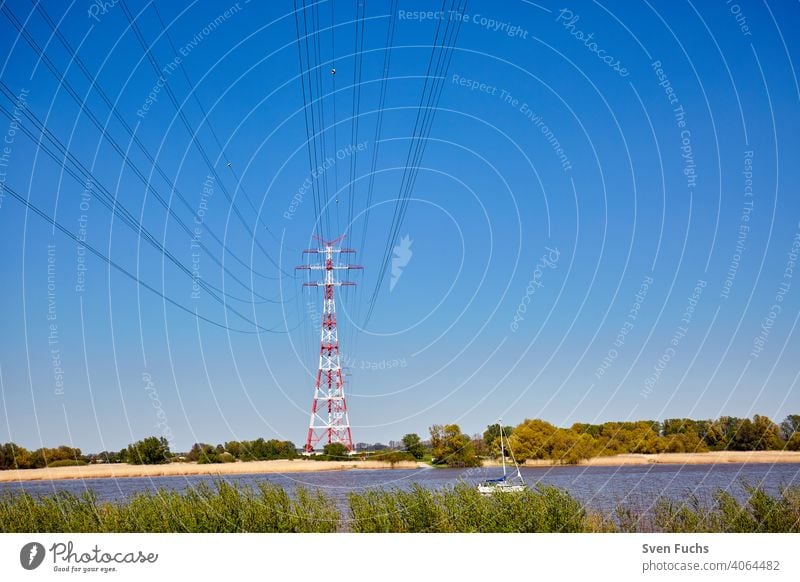 Red and white electricity pylons stand on the Elbe River Electricity pylon stream Energy power line energy revolution Germany Hamburg Force towering