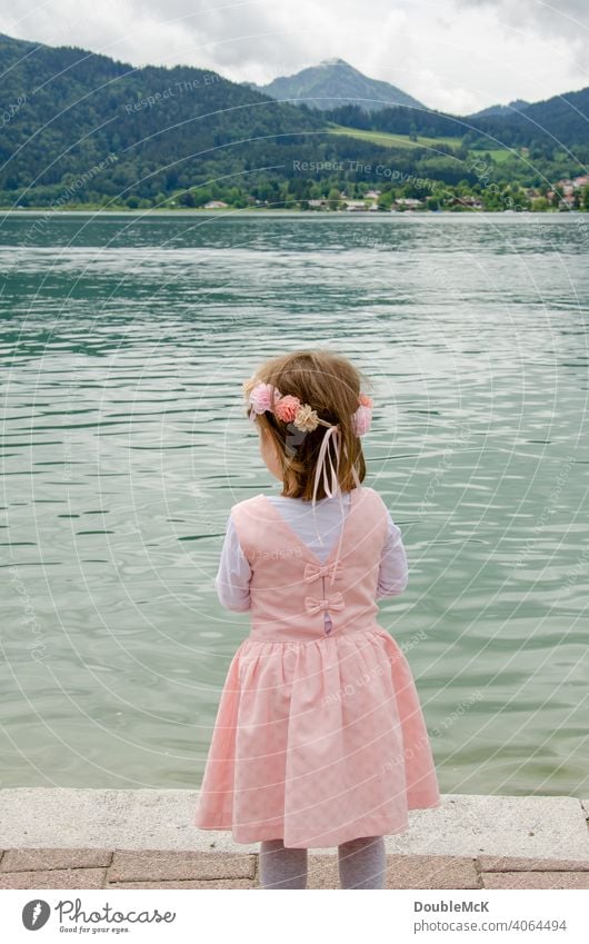 A girl with a wreath of flowers stands by the lake and looks into the distance Colour photo Girl Human being Dress up Infancy Crown Happiness muck about Child