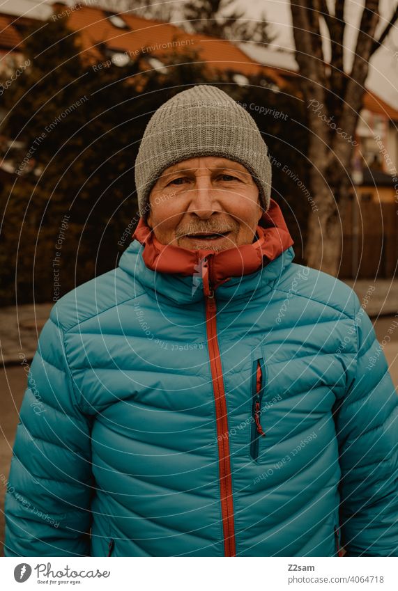 Portrait of a sporty pensioner Pensioners Athletic Man age down jacket Winter chill Cap Laughter kind naturally portrait out warm colors sincerely free time