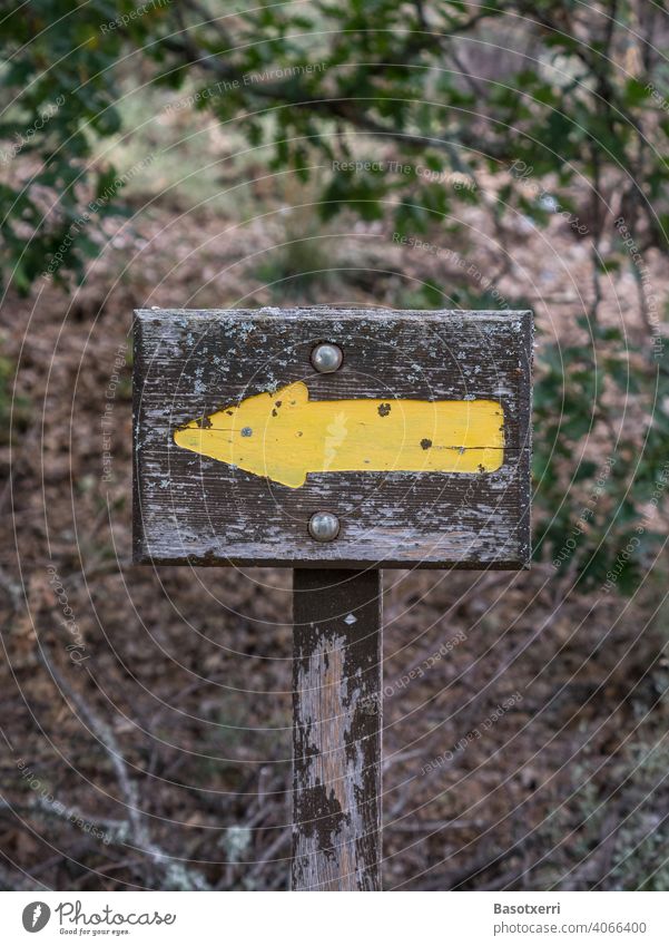 Yellow arrow pointing to the left as trail marker on a hiking trail in the forest Arrow yellow arrow Forest Hiking off path Orientation Information Left sign