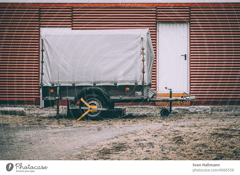 trailer stands in front of building anhänger orange rad tür wand Trailer Means of transport Transport Vehicle lorry Logistics Truck Mobility Parking Tire Street