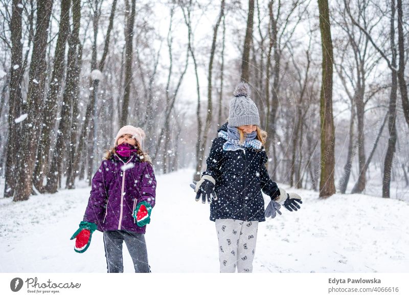 Children throwing snow in the air and enjoying a cold winter day daughter two laughing friends enjoyment activity playful kids smiling snowflakes together