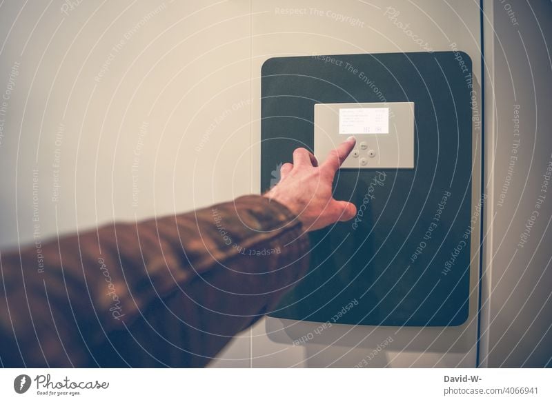 Man adjusts heating regulator / control unit of an air heat pump - renewable energy - modern heating technology Heating controller Air source heat pump