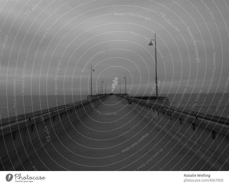 Deserted fishing pier water ocean beach stucture dark desolate somber gloomy still empty eerie lonely deserted waterfront sea landscape black and white