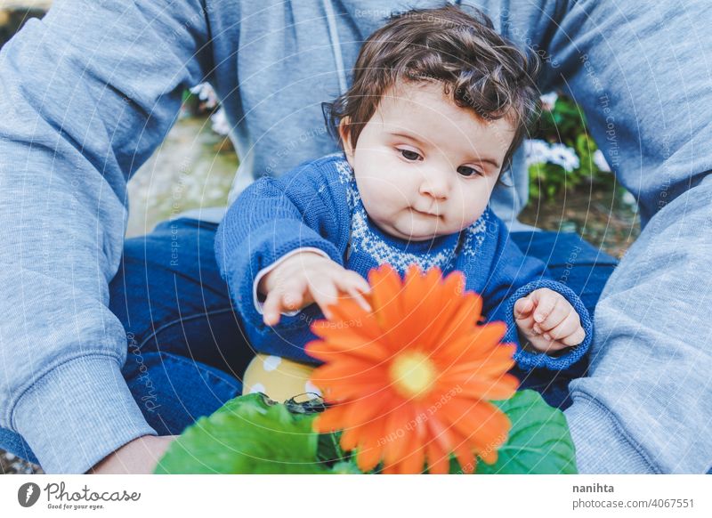 Little baby discovering a huge flower for first time spring happiness family family time dad father girl kid child toddler 9 month casual candid wear life