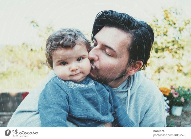 Young dad enjoying a sunny day with his baby in the garden father family love happiness kiss care caring parenting lovely cute outdoors spring spring time