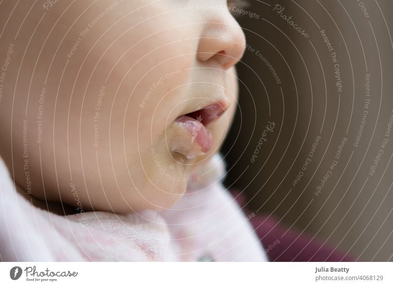 Profile of a young baby's face; baby is teething and drooling as she looks out the window child cute kid boy newborn portrait damp wet lips nose mouth open