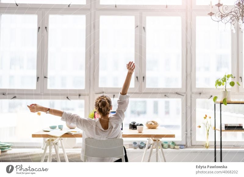 Rear view of young woman working on laptop in loft office millennials student hipster indoors window natural girl adult one attractive successful people