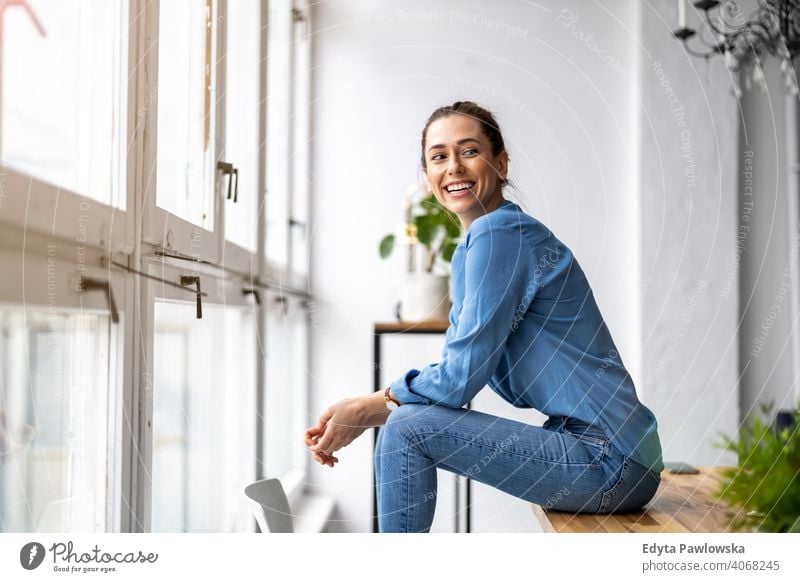 Portrait of a smiling creative woman in a modern loft space millennials student hipster indoors window natural girl adult one attractive successful people