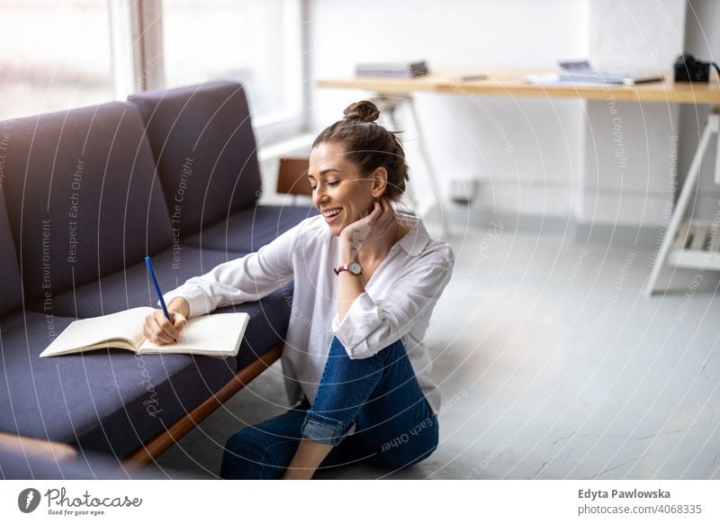 Young woman doing homework on sofa sitting couch resting relaxing comfortable millennials student hipster indoors loft window natural girl adult one attractive